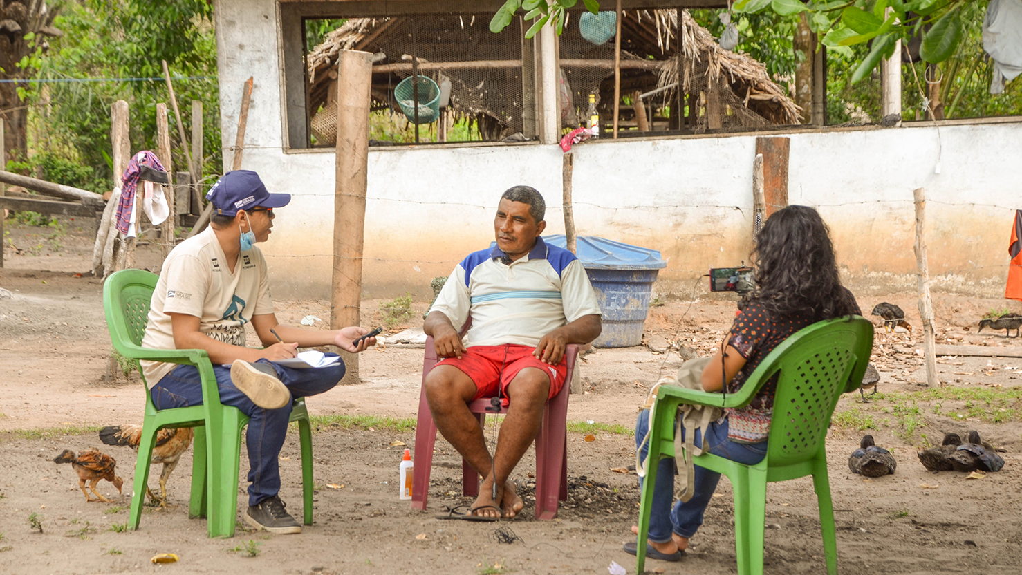 Membro da equipe entrevistando dois moradores locais para realizar diagnóstico socioambiental